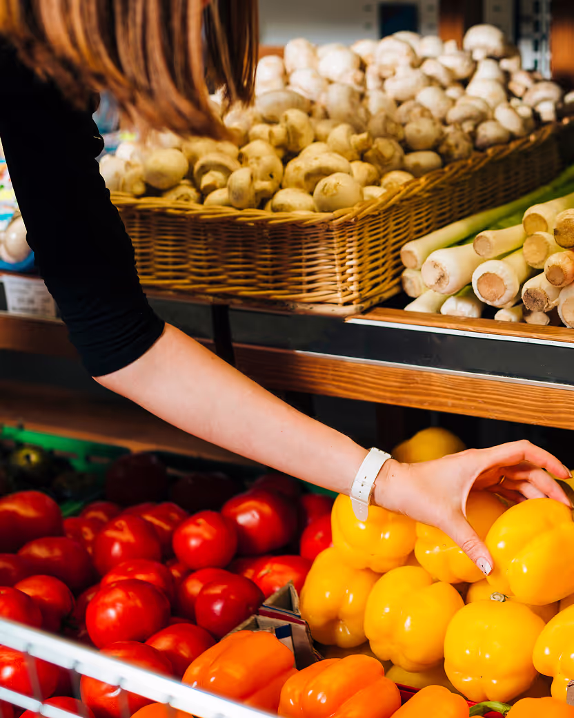 a photo of a woman picking fresh vegetables inside a grocery store